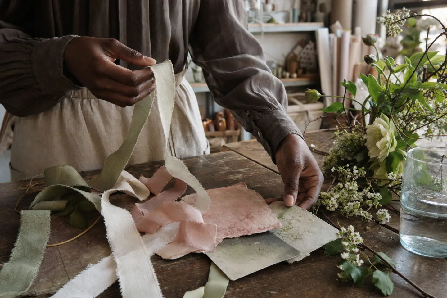 Amara handles ribbon swatches and pressed color references beside fresh spring stems.